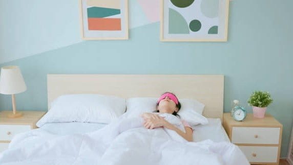 Closeup asian woman waking up in the morning - she use sleep mask with satisfaction and good sleep quality