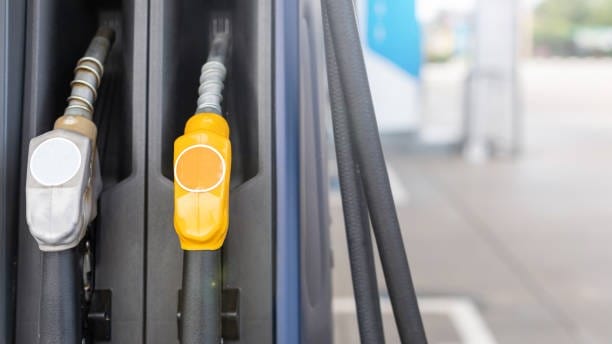 Close up fuel nozzle in Petrol station. Soft focus on blur day light background with space for text. Energy or transportation concept