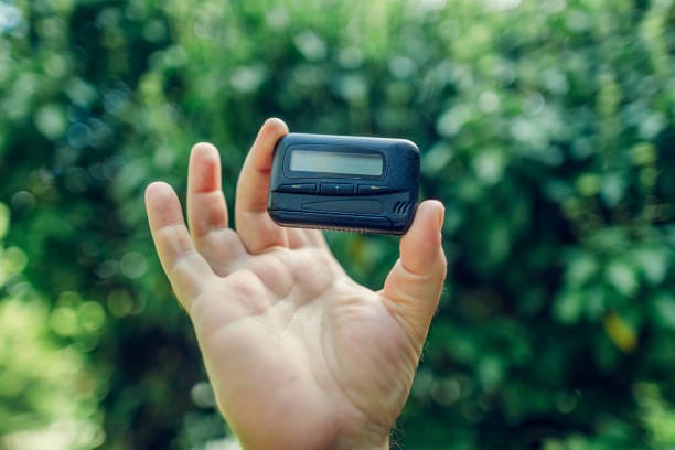 vintage technique. vintage gadget pager. pager in hand on green background