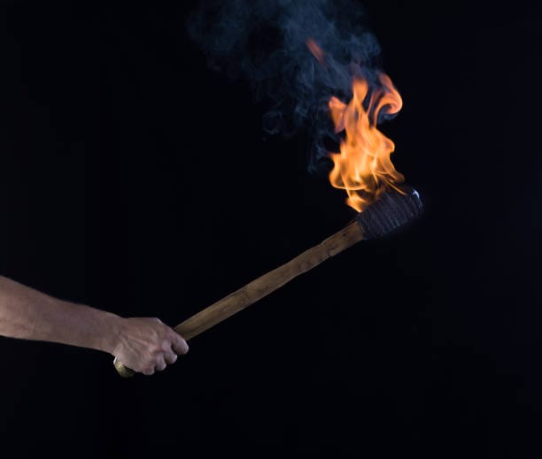 burning wooden torch in hand isolated on black background