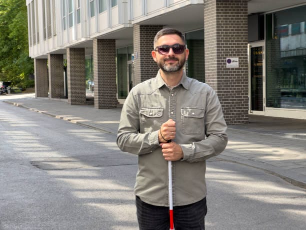 Portrait of a mid-adult Caucasian man with visual impairments, holding a cane