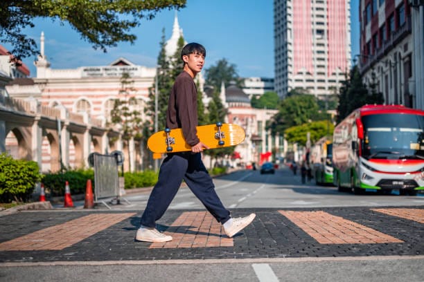 Young hipster boy crossing the street riding the skateboard in the urban city