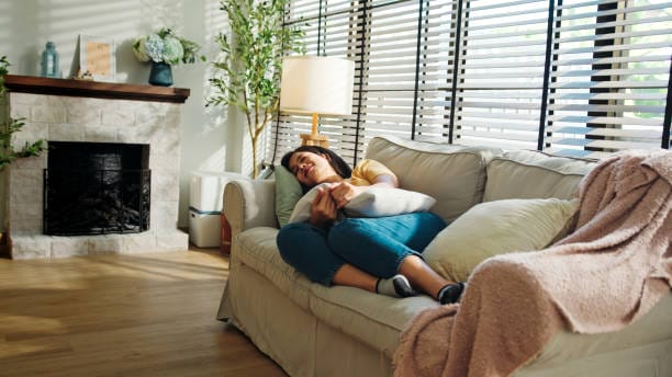 Woman Enjoying a Peaceful Nap on a Couch in a Bright Living Room