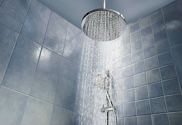 Low angle of running water from shower head in a cool coloured shower