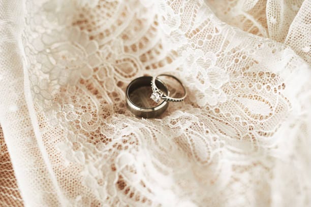 Still life shot of two beautiful wedding rings on top of a wedding dress