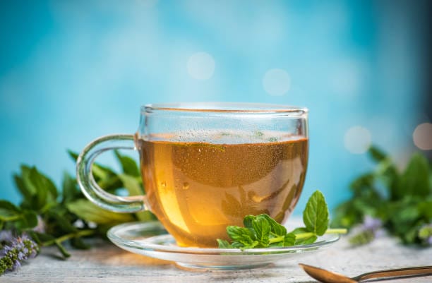 Mint tea in a glass teacup against blue background on a table with copy space