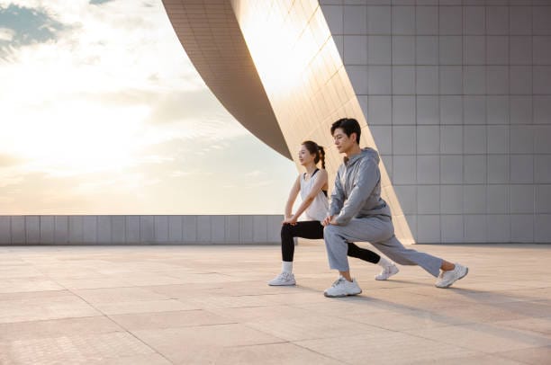 A young asian couple is preparing for running training. They stretched themselves in the sun and were in a good mood.The shooting place is in Zhengzhou, China, which is the citizen fitness center. It is a public open area.